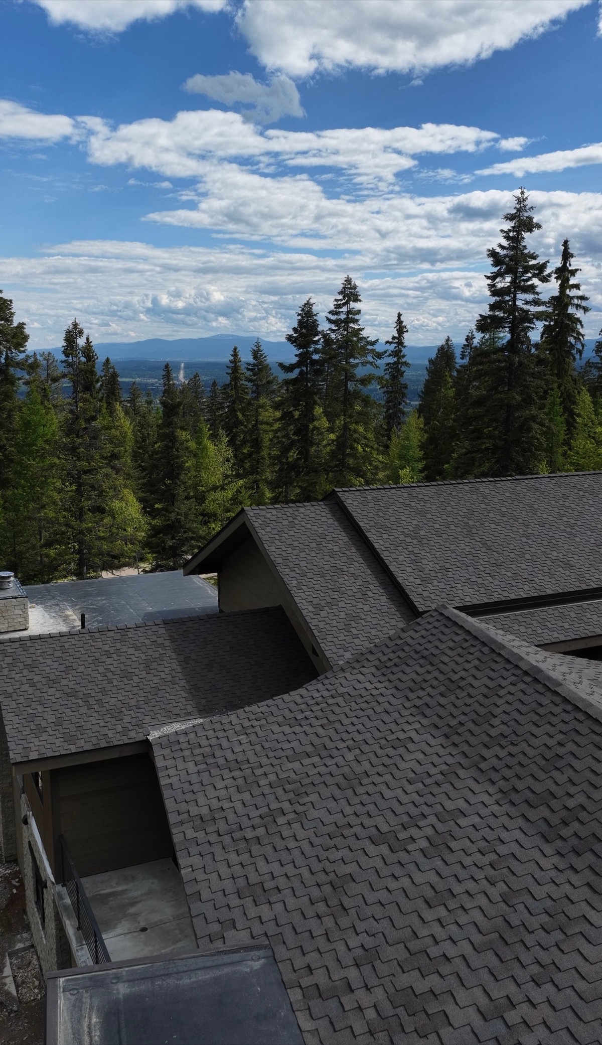Architectural shingle across a multi-gable roof, with the valley beyond